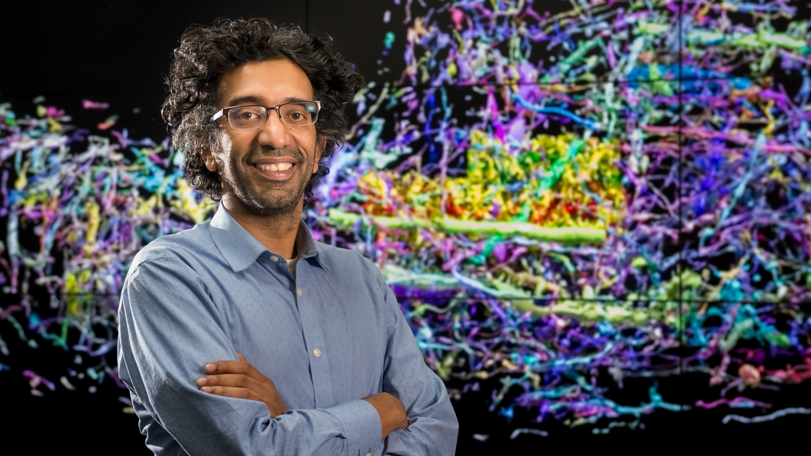 Neuroscientist Bobby Kasthuri in front of images from his work to map every single cell in a human brain.