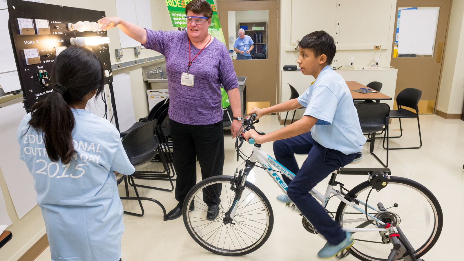 Seventh-grade students peddling bicycle to power various types of lightbulbs as part of an introduction to science and Argonne National Laboratory.