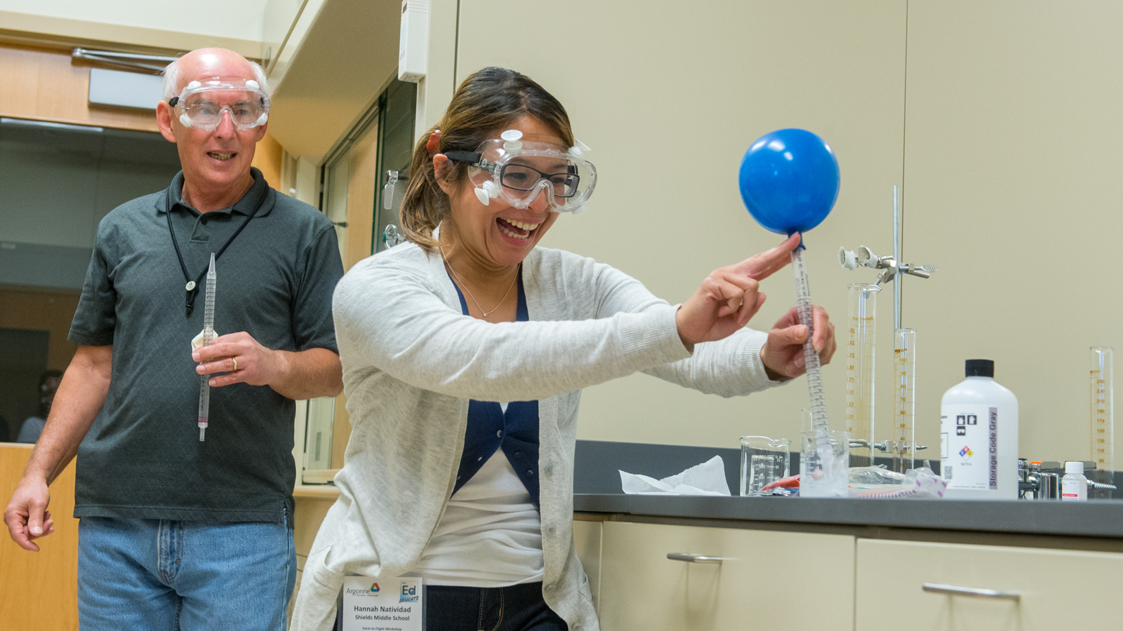 Argonne’s Deon Ettinger shows Shields Middle School teacher Hannah N. how the air she exhaled into the balloon reacts with the calcium hydroxide solution in the glass beaker to create calcium carbonate. The reaction, which turned a transparent solution into a chalky-colored one, is an indicator of the presence of carbon dioxide and shows when carbon-based substances (like biofuels) are used as fuel, carbon dioxide is released. Photo credit: Mark Lopez, Argonne National Laboratory.