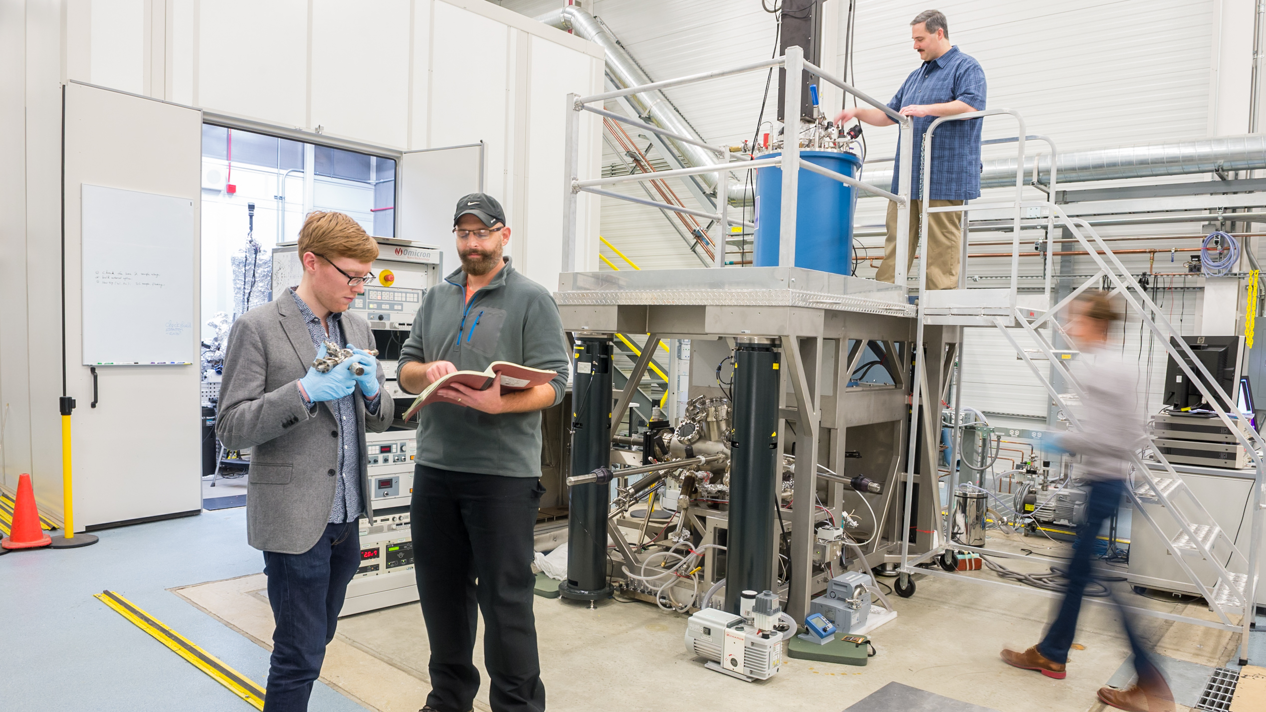 Andrew Mannix and Nathan Guisinger examine a boron evaporator while Brandon Fisher checks cryogen flow settings and Brian Kiraly examines a sample next to a vacuum chamber loadlock at the Center for Nanoscale Materials. Photo by Mark Lopez / Argonne National Laboratory.