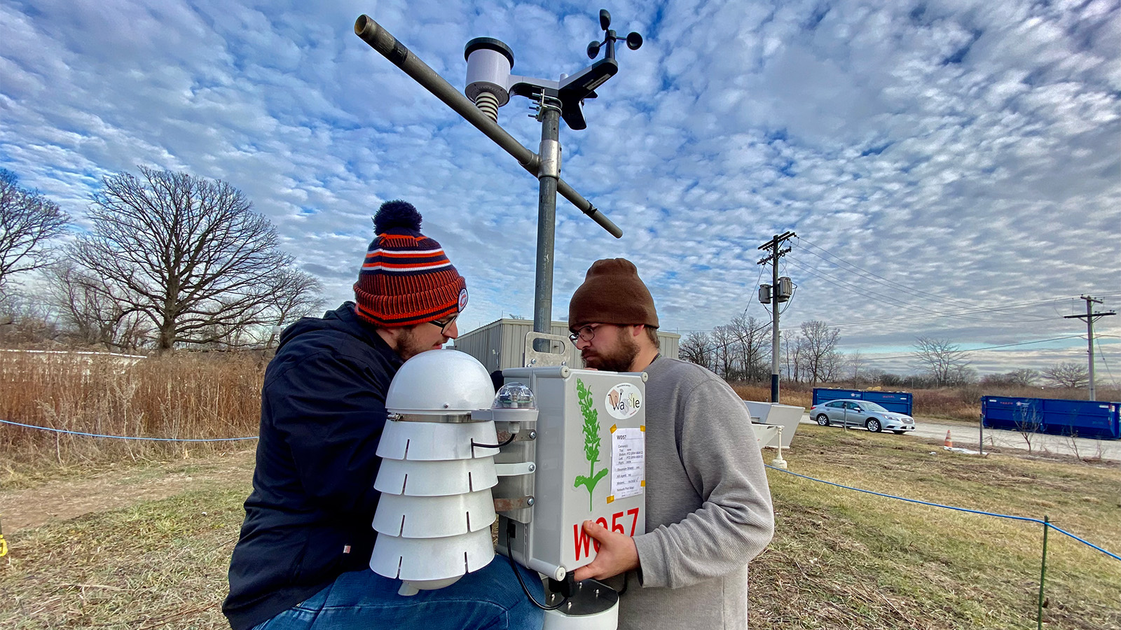 Matt Tuftedal and Joe O’Brien working on a SAGE node with a low-cost weather station mounted on the pole