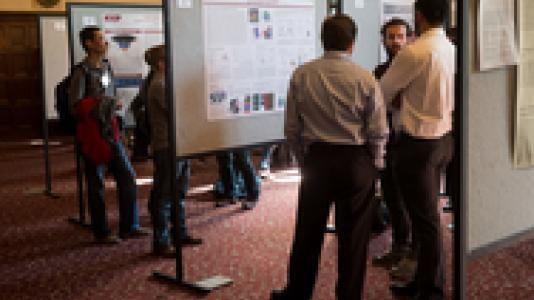 Photograph of people looking at posters at a symposium.