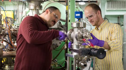 Argonne National Laboratory scientist Sergey Chemerisov (left) works with Ian Hamilton (right), CEO of Atlas Energy Systems and a member of Chain Reaction Innovation to set up a system to generate ionized gas from the Van de Graff Accelerator at Argonne.