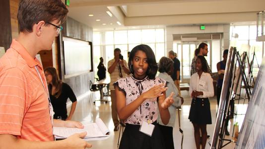 Whitney Ford, a senior at Plainfield East High School, explains her award-winning research during the event to honor students and volunteers of the Argonne Afro-Academic, Cultural, Technological and Scientific Olympics (ACT-SO) High School Research Program.