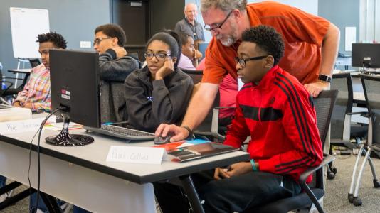 Mike Papka, director of the Argonne Leadership Computing Facility, works with high school students at coding camp. Students learned the Python programming language, among other problem-solving skills related to computer science.