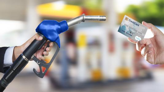 Photo of gas pump handle and credit card. (Image by Shutterstock/Naypong Studio.)