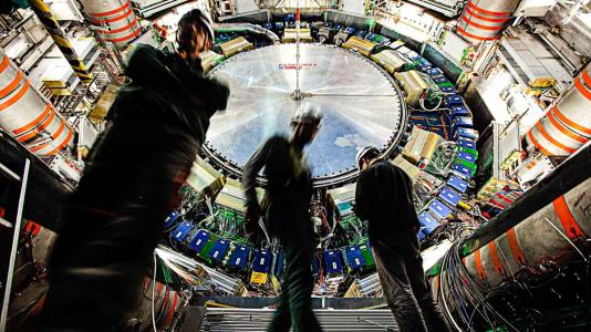Workers inside ATLAS, one of several primary detectors for the Large Hadron Collider at CERN. ATLAS witnesses a billion particle interactions every second and the signatures of new particles created in near-speed-of-light proton-proton collisions. (Image by CERN.)